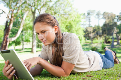 Woman with a tablet computer lying on the lawn