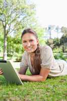 Smiling woman lying on the grass with her tablet computer