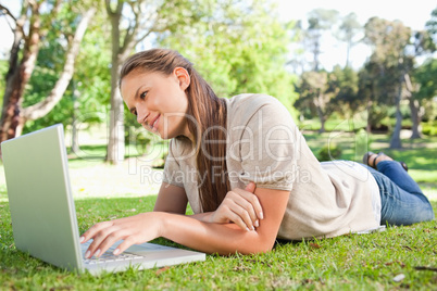 Woman lying on the lawn with her laptop