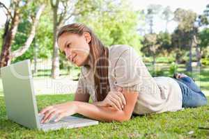 Woman lying on the lawn with her laptop