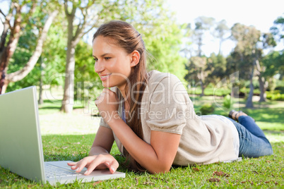 Smiling woman lying on the lawn with her notebook