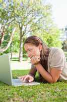Woman lying on the lawn while using her laptop