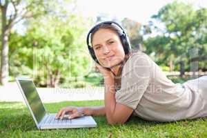 Side view of a woman with her laptop and headphones lying on the