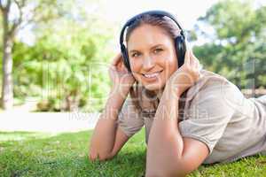 Woman with headphones lying on the lawn