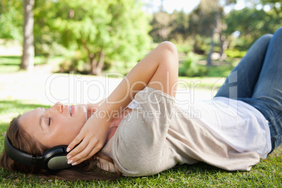 Woman lying on the lawn while enjoying music