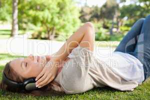 Woman lying on the lawn while enjoying music