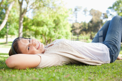 Woman lying on the grass while listening to music