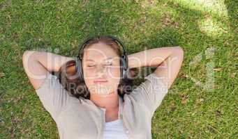 Relaxed woman listening to music while lying on the lawn