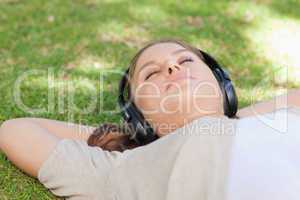 Relaxed woman lying on the lawn enjoying music