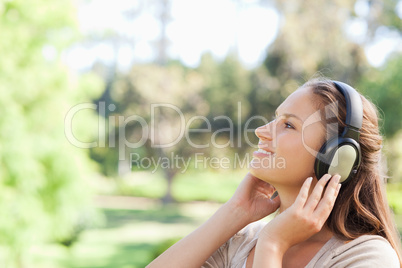 Side view of a woman in the park enjoying music