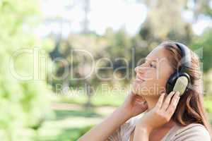 Side view of a woman in the park enjoying music