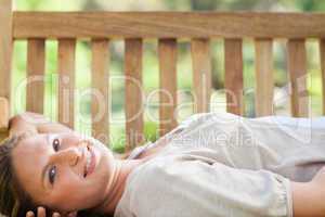 Smiling woman lying on a park bench