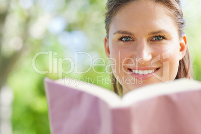 Smiling woman reading a book in the park