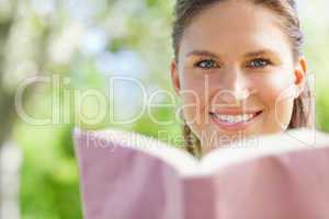 Smiling woman reading a book in the park