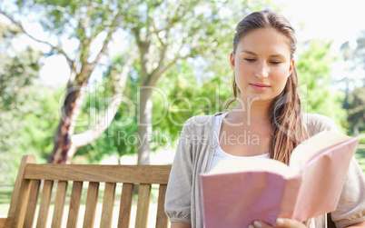 Woman sitting on a park bench while reading a book