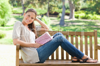 Side view of a smiling woman sitting on a park bench with her bo