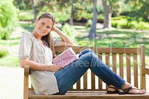 Side view of a smiling woman sitting on a park bench with her bo