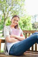 Smiling woman sitting on a park bench with her book