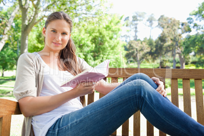 Woman sitting on a park bench with a book