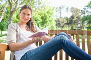 Woman sitting on a park bench with a book