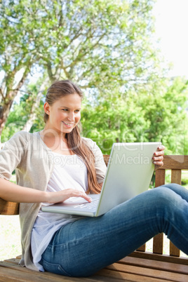 Smiling woman with her laptop sitting on a bench