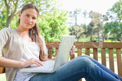 Woman with a laptop sitting on a park bench