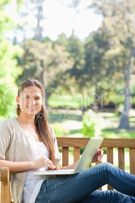 Smiling woman with her notebook on a park bench