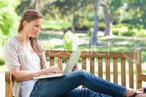 Woman on a park bench working on her laptop