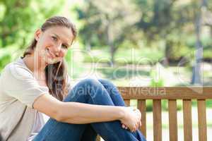 Smiling woman sitting on a park bench