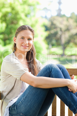 Smiling woman enjoying the sun on a park bench