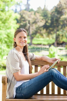 Side view of a smiling woman with a tablet computer on a park be