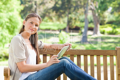 Side view of a woman with a tablet computer on a park bench