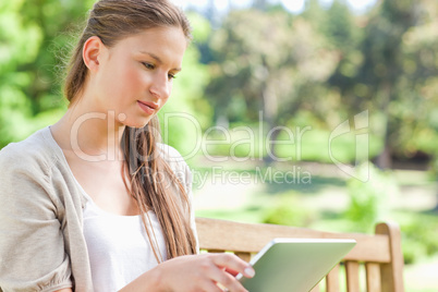 Woman with her tablet computer sitting on a park bench