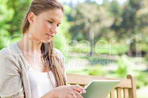 Woman with her tablet computer sitting on a park bench
