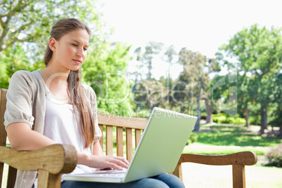 Woman with a laptop on a park bench