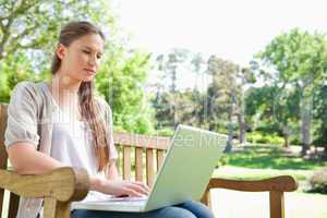 Woman with a laptop on a park bench
