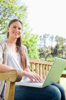 Smiling woman with her notebook sitting on a park bench
