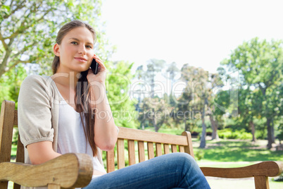 Woman on her phone on a park bench
