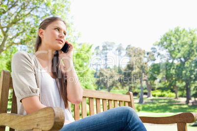 Woman talking on her phone on a park bench