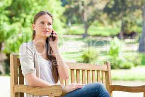 Woman on her mobile phone on a park bench