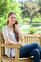 Smiling woman sitting with her mobile phone on a park bench