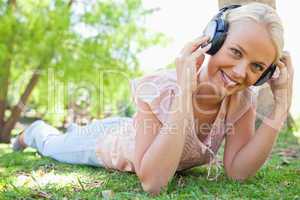 Smiling woman enjoying music on the grass