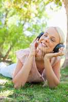 Smiling woman with headphones enjoying music on the lawn