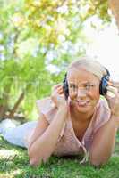 Smiling woman with headphones enjoying music on the grass