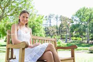 Smiling woman enjoying her day on a bench in the park