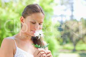 Woman smelling on a flower in the park