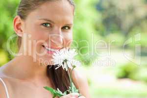 Smiling woman with a flower in the park