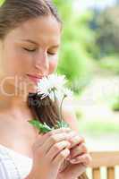 Close up of a woman smelling a flower in the park