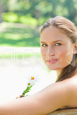 Side view of a woman holding a flower in the park