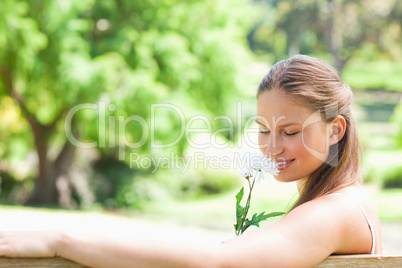 Side view of a woman smelling a flower
